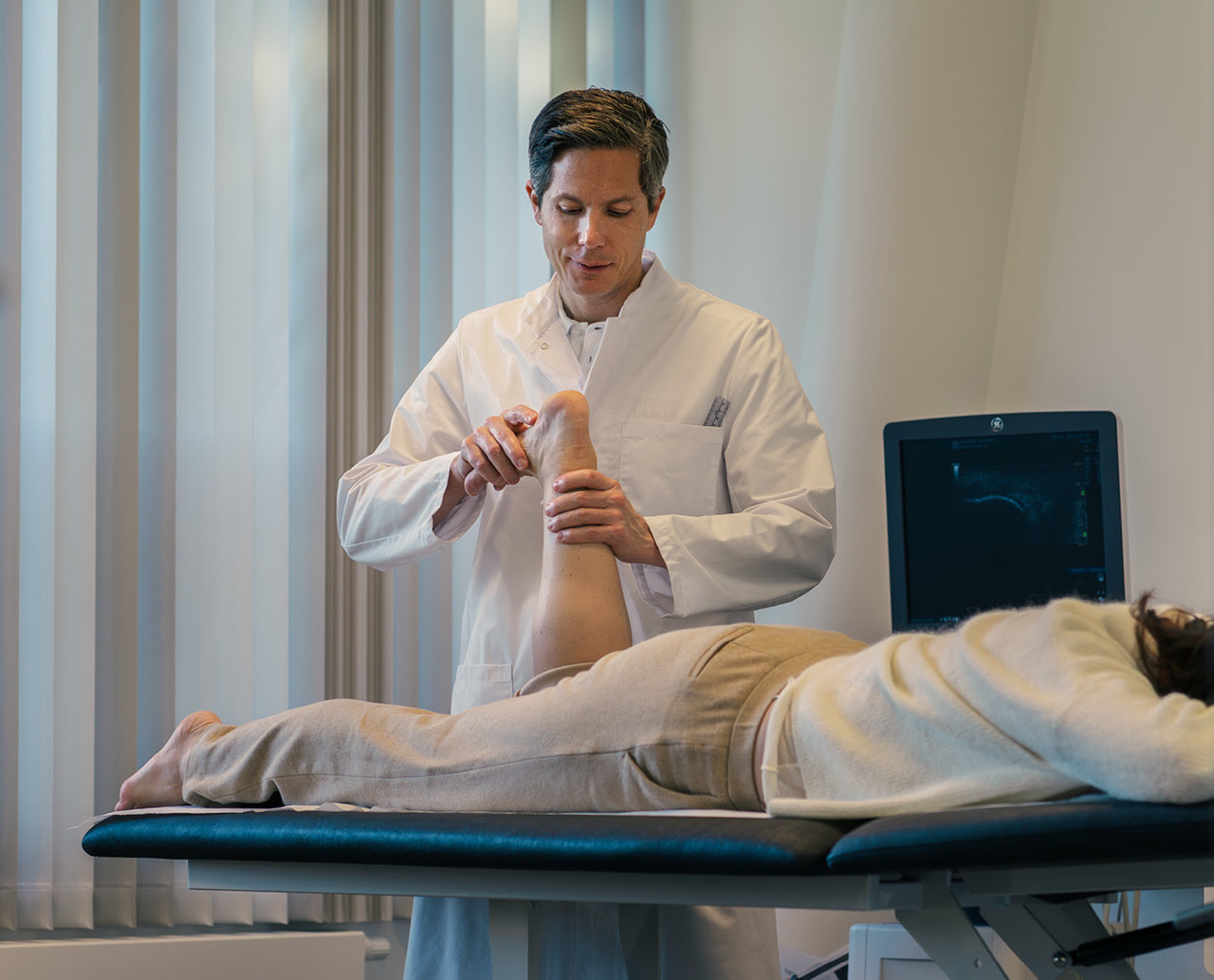 Dr. Pallamar untersucht ein Fußgelenk im professionell ausgestatteten Ordinationsraum des das Moritz.